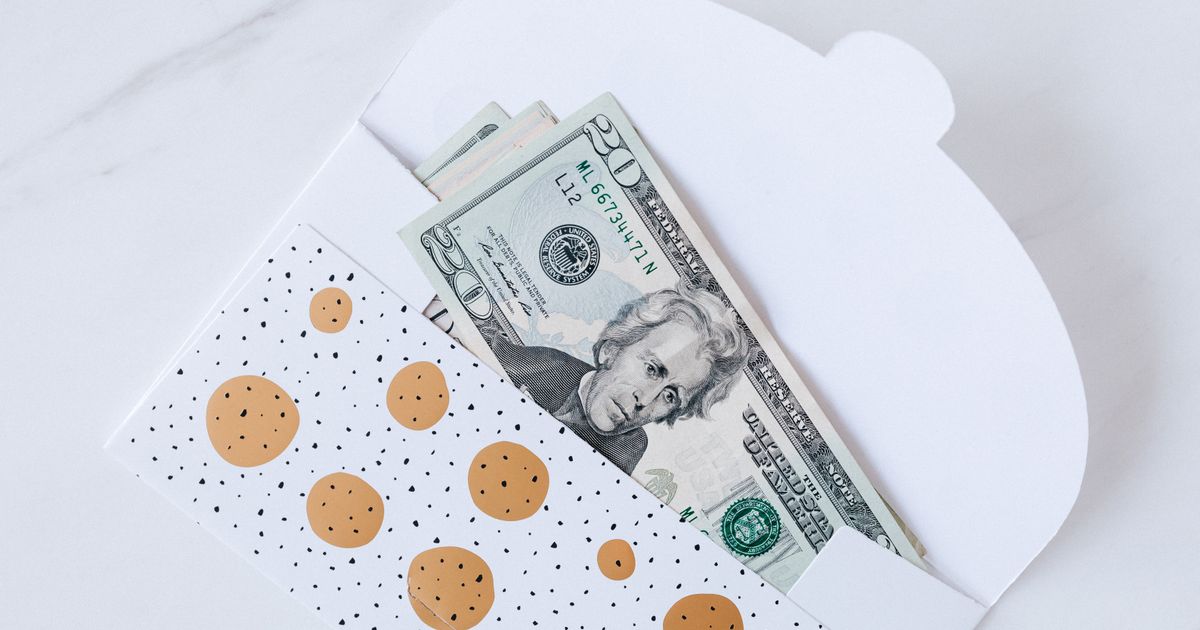 Banknotes tucked into a white gift envelope on a marble table