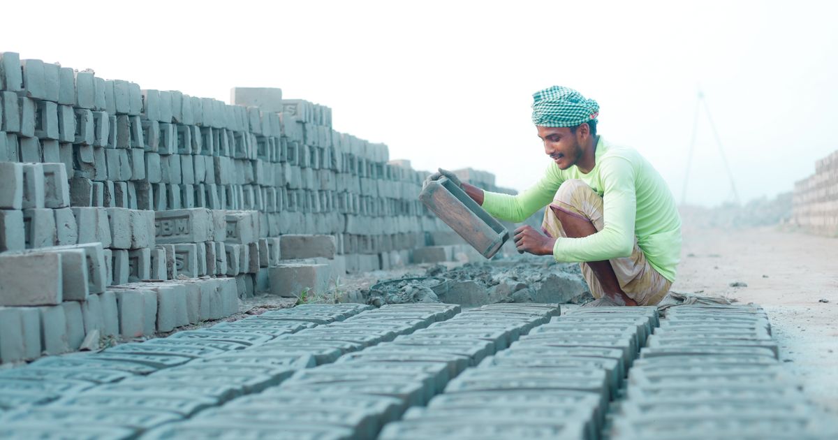 A worker setting bricks into place on an open-air building site