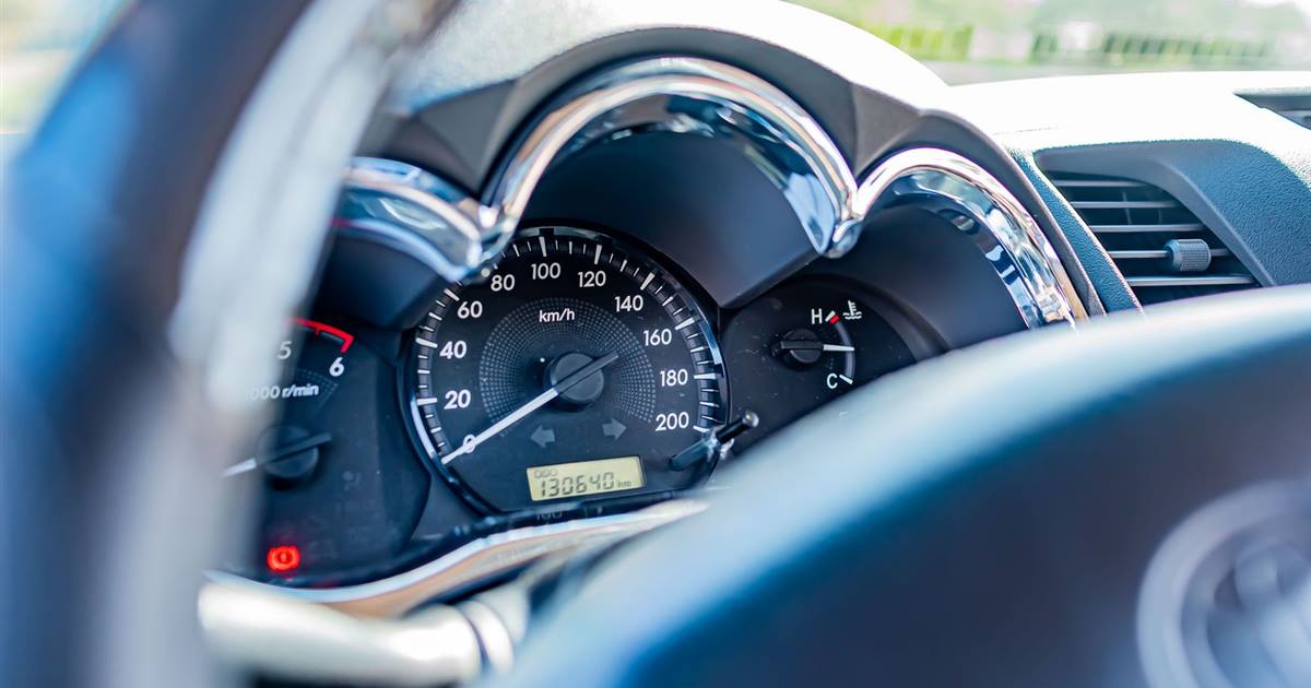 Close-up of a car speedometer and odometer seen past the steering wheel