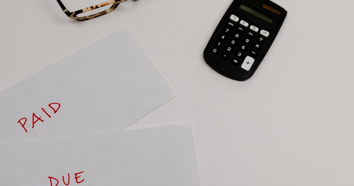 Top view of papers stamped Paid and Due beside a calculator and a pair of glasses