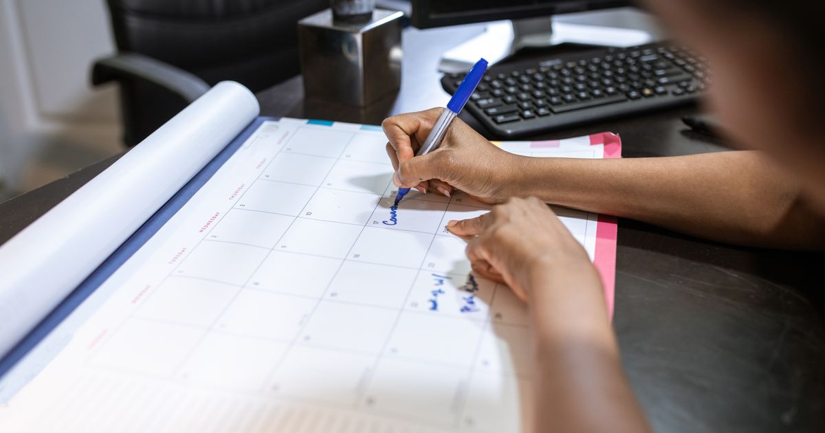 A woman writing in a desk calendar while planning her schedule
