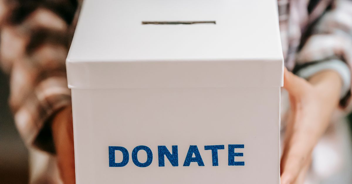 A person holding a cardboard donation box out towards the camera