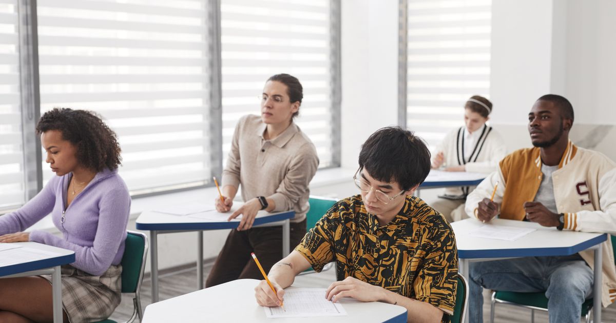 A group of students writing exam papers in a well-lit classroom
