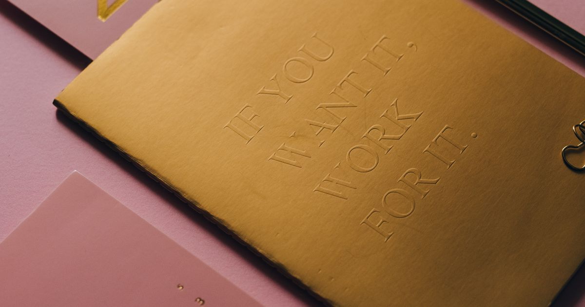 A desk calendar and notebook on a pink background