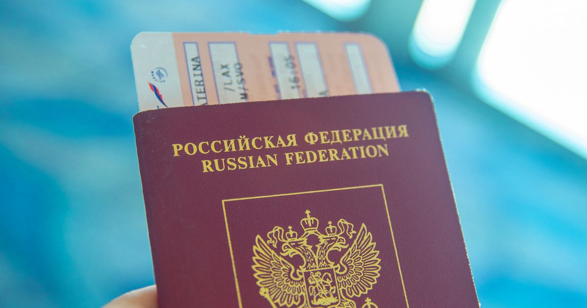 A hand holding a passport with a boarding pass tucked inside