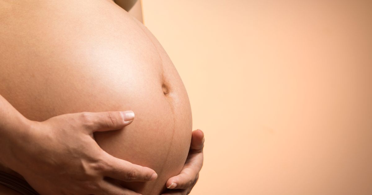 Close-up of a pregnant woman's hands resting on her belly