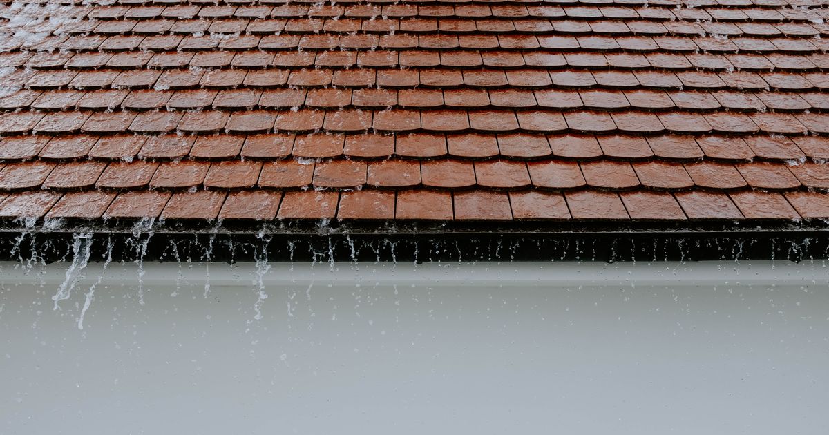 Rainwater running down brown clay roof tiles