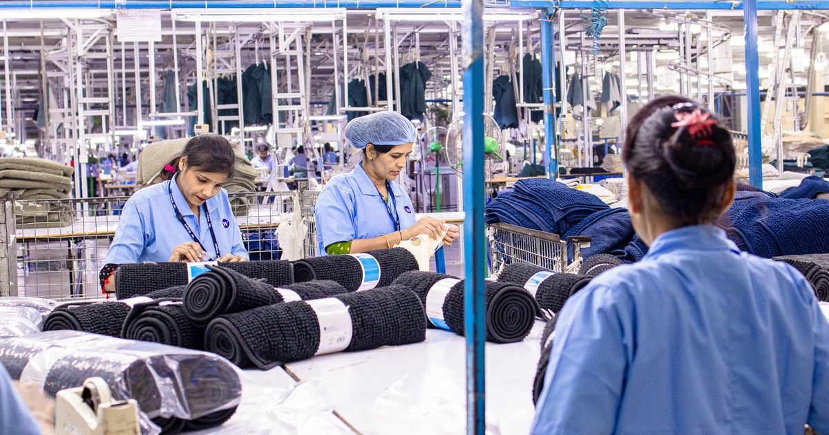 Workers in blue uniforms rolling and packing textiles in a large factory